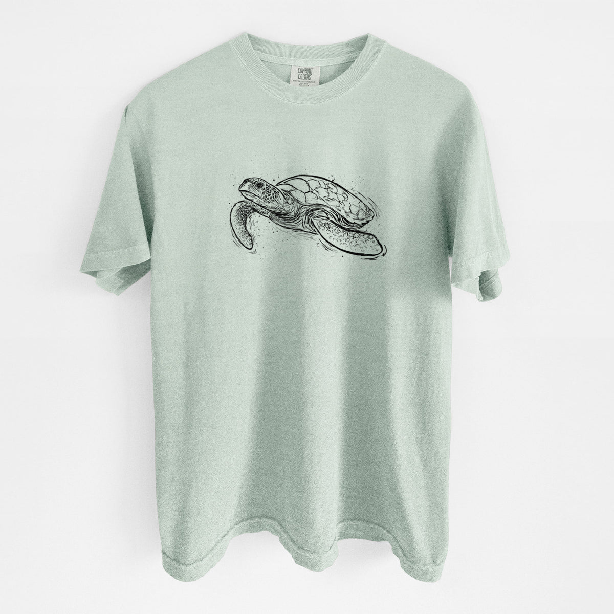 Bay green Comfort Colors t-shirt laid flat, printed with a black ink illustration of a hawksbill sea turtle swimming, with a patterned shell.