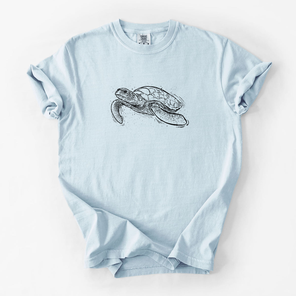 Chambray blue Comfort Colors t-shirt laid flat, printed with a black ink illustration of a hawksbill sea turtle swimming, with a patterned shell.