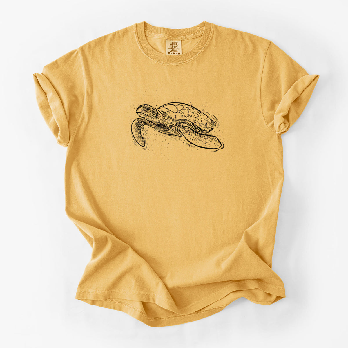 Golden wheat yellow Comfort Colors t-shirt laid flat, printed with a black ink illustration of a hawksbill sea turtle swimming, with a patterned shell.