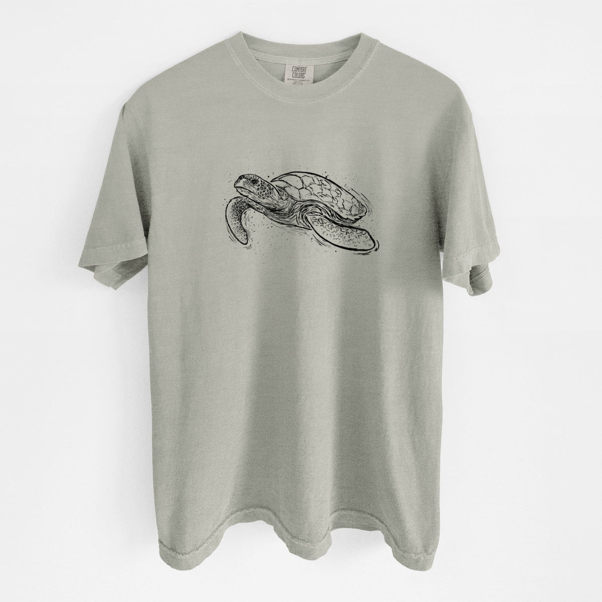 Sandstone beige Comfort Colors t-shirt laid flat, printed with a black ink illustration of a hawksbill sea turtle swimming, with a patterned shell.