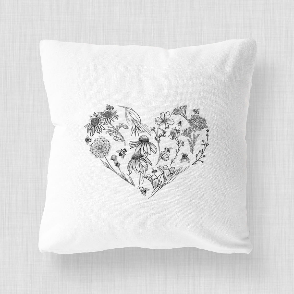 White pillow cover printed with a heart shape filled with black ink flowers and bees.