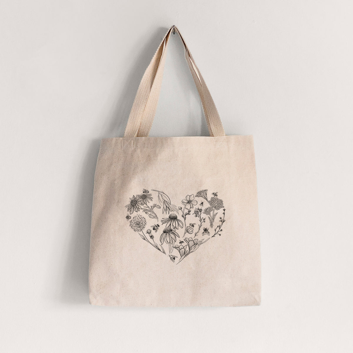 Natural canvas tote bag printed with a heart shape filled with black ink flowers and bees.
