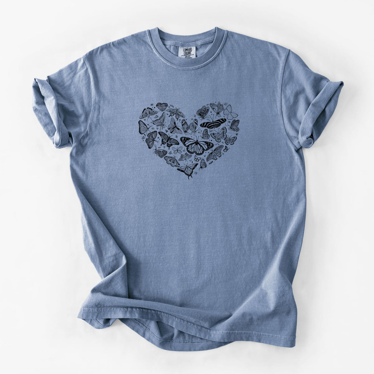 Blue jean Comfort Colors t-shirt laid flat, printed with a heart shape filled with small black ink butterflies and moths.