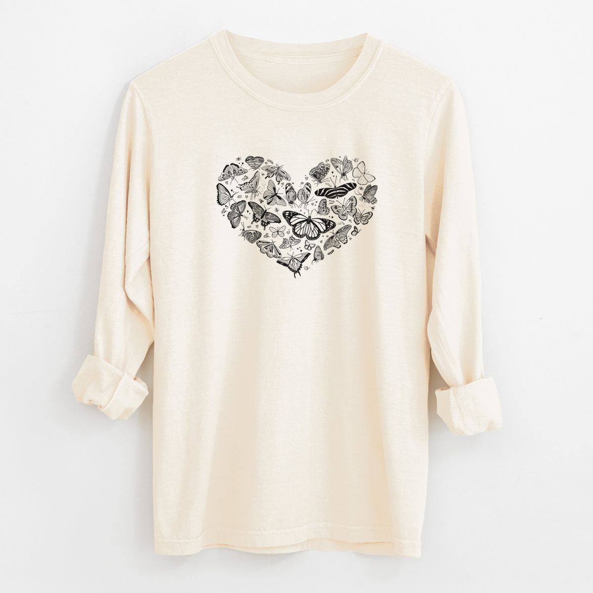 Ivory Comfort Colors long sleeve shirt laid flat with the cuffs rolled, printed with a heart shape filled with small black ink butterflies and moths.