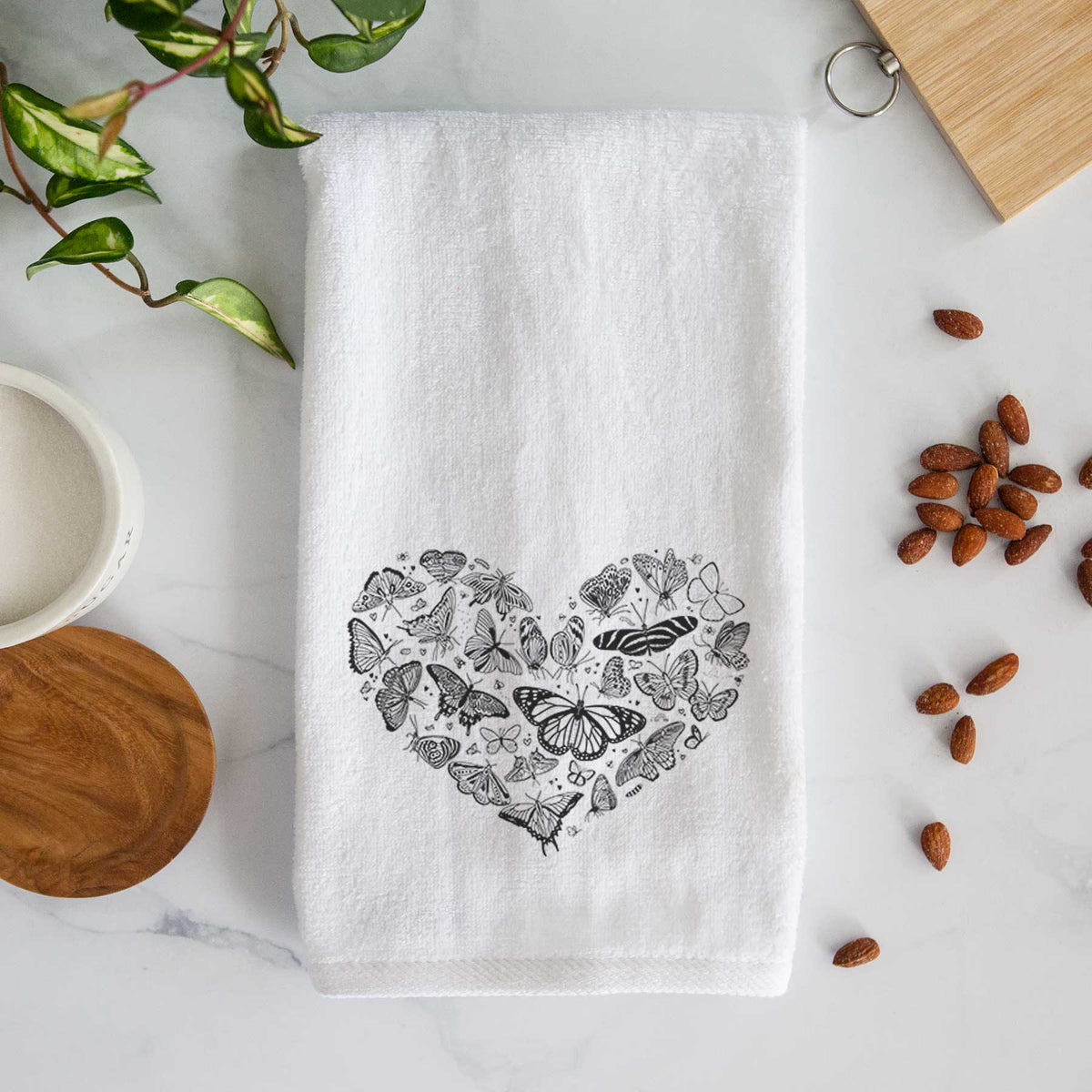 White hand towel printed with a heart shape filled with small black ink butterflies and moths.