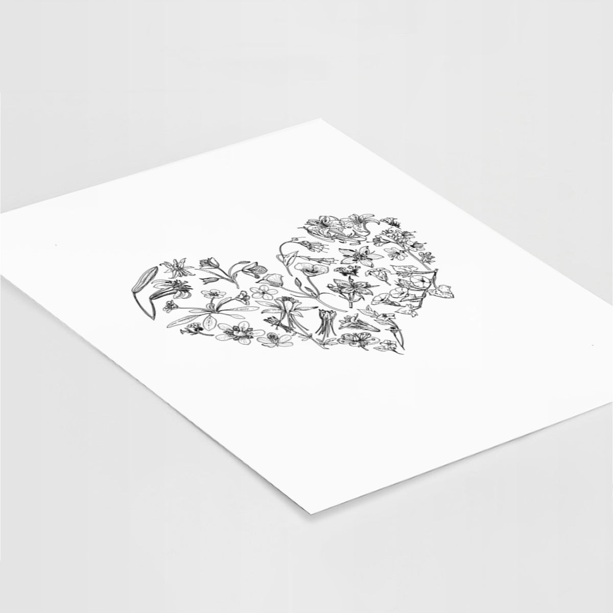 Art print of a heart shape filled with black ink California mountain wildflowers, lying at an angle on a white surface.