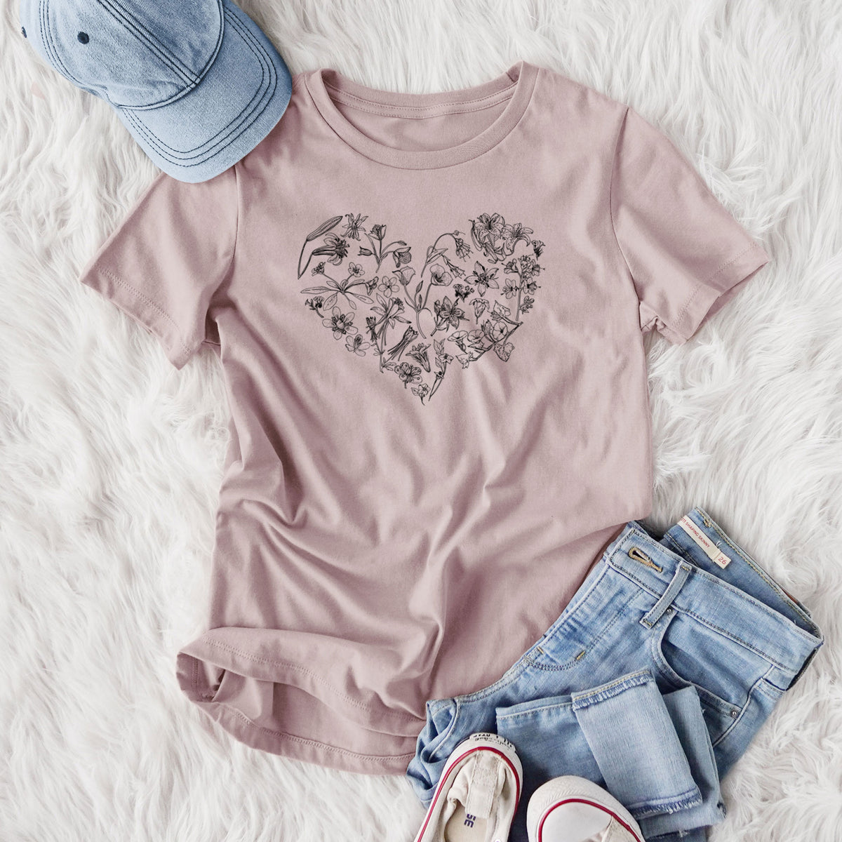 Women's relaxed fit cotton t-shirt printed with a heart shape filled with black ink California mountain wildflowers, styled flat on a white faux fur rug with jeans.