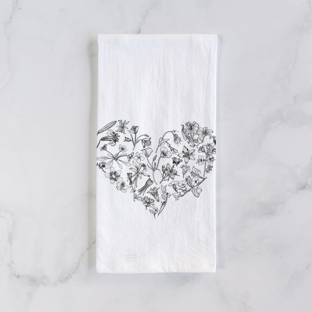 White cotton tea towel laid flat on marble, printed with a heart shape filled with black ink California mountain wildflowers.
