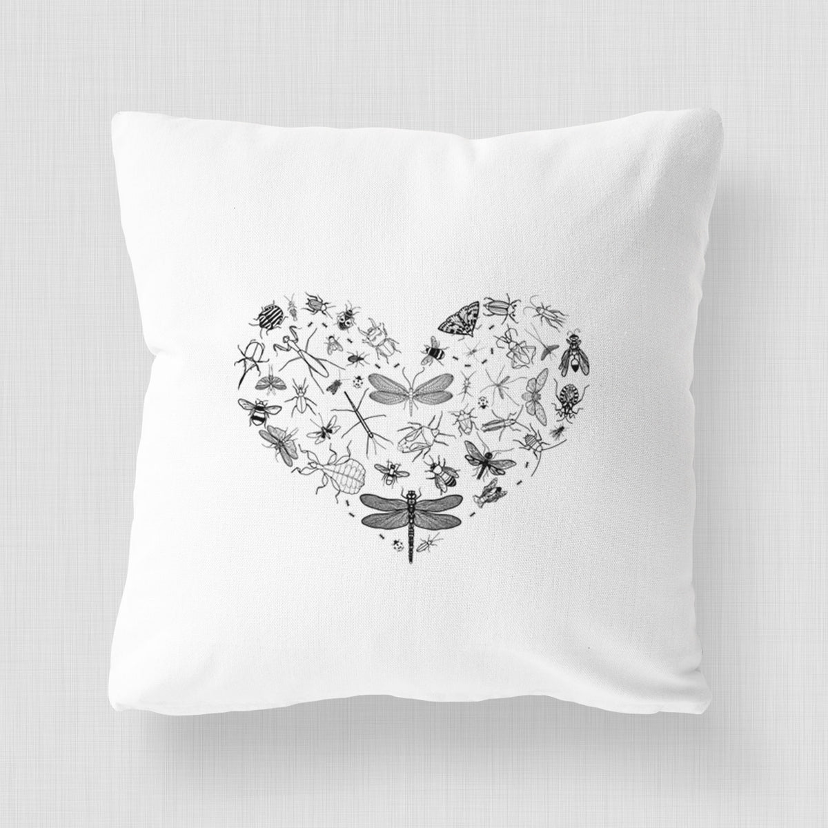 White pillow cover printed with a heart shape filled with small black ink insects, including dragonflies, beetles and bees.