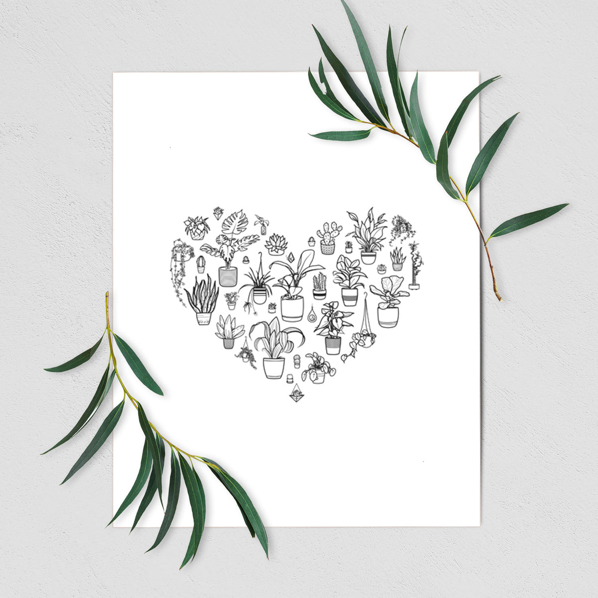 Art print of a heart shape filled with black ink potted houseplants, shown with eucalyptus leaves.