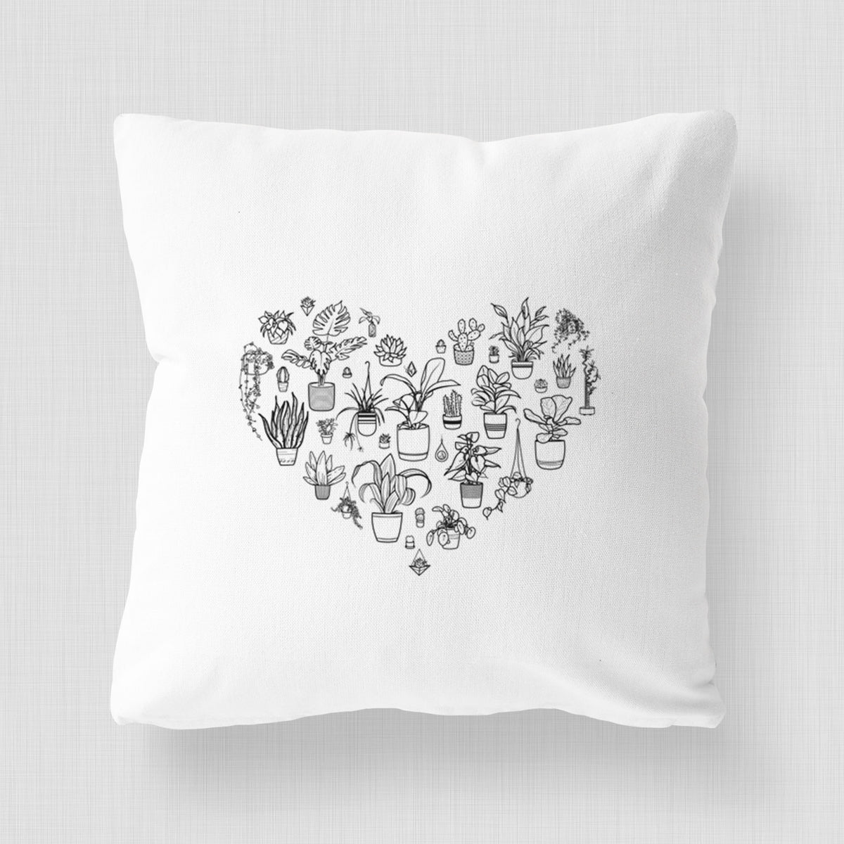 White pillow cover printed with a heart shape filled with black ink potted houseplants.