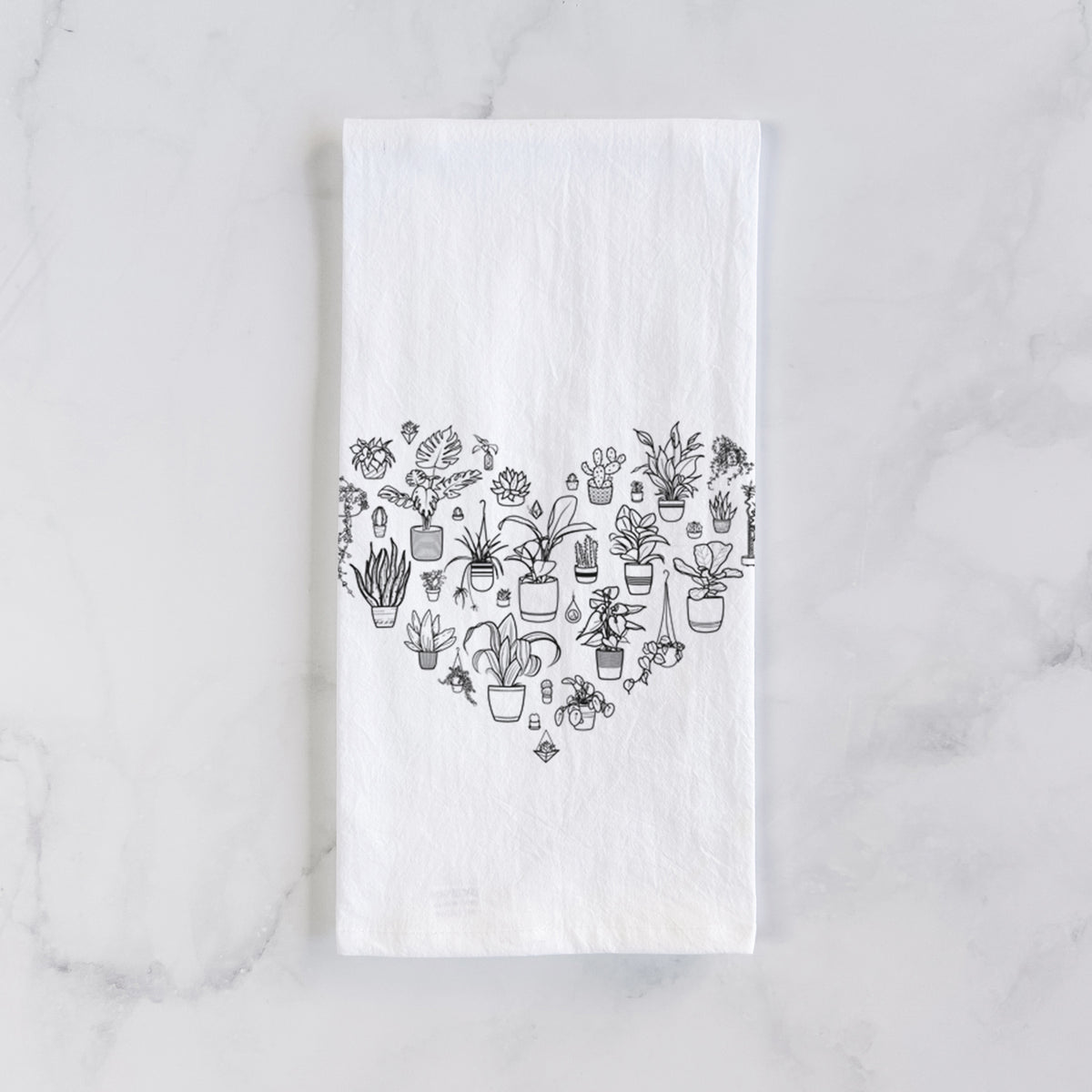 White cotton tea towel laid flat on marble, printed with a heart shape filled with black ink potted houseplants.