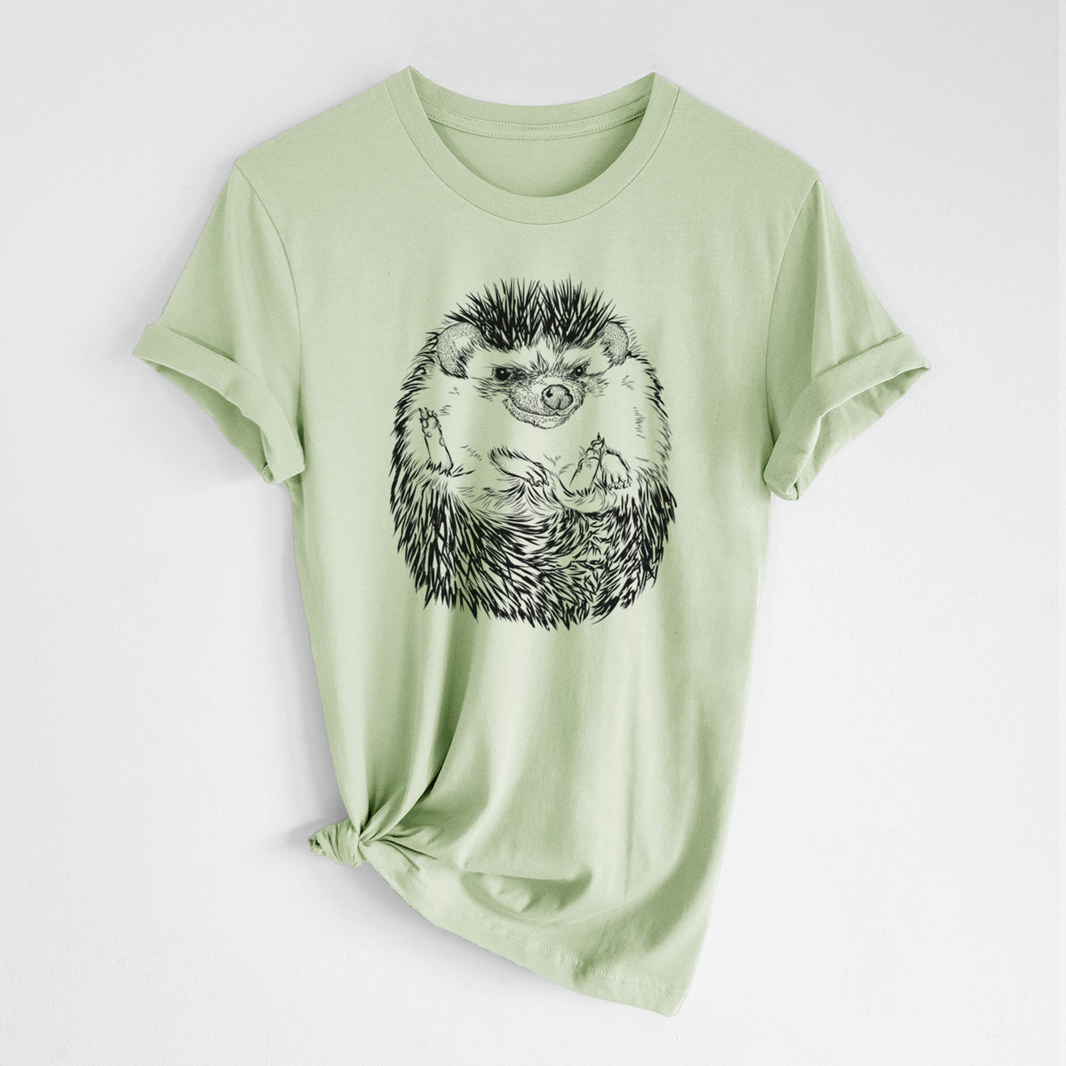 Spring green lightweight cotton t-shirt laid flat with the sleeves rolled, printed with a detailed black ink illustration of a hedgehog curled up and facing forward.