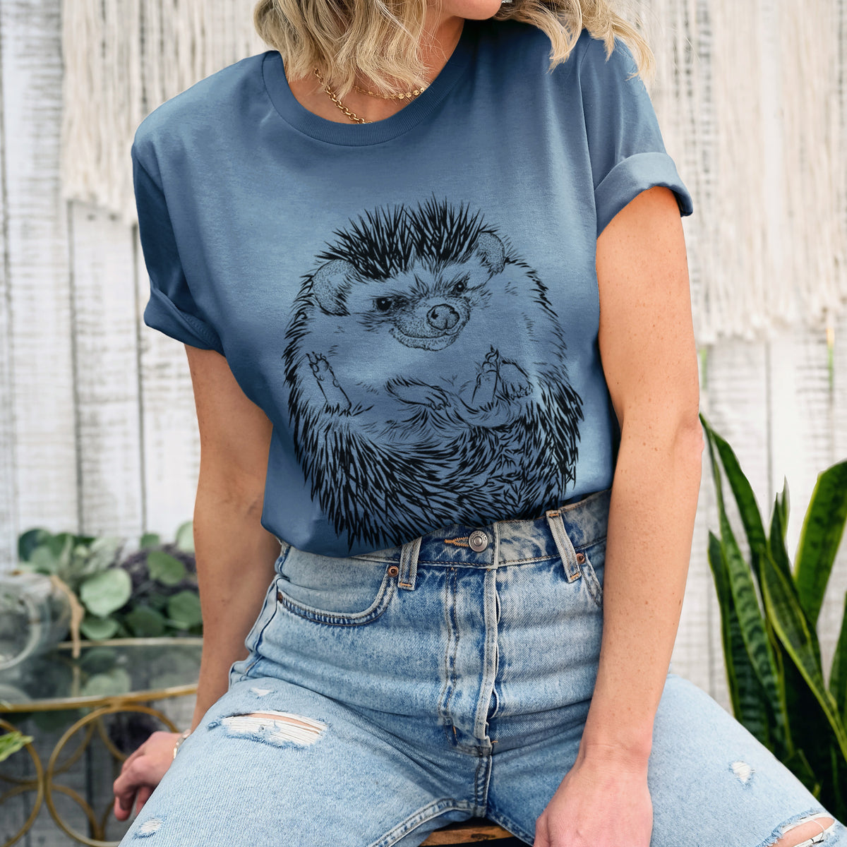 Woman wearing a steel blue lightweight cotton t-shirt printed with a detailed black ink illustration of a hedgehog curled up and facing forward.