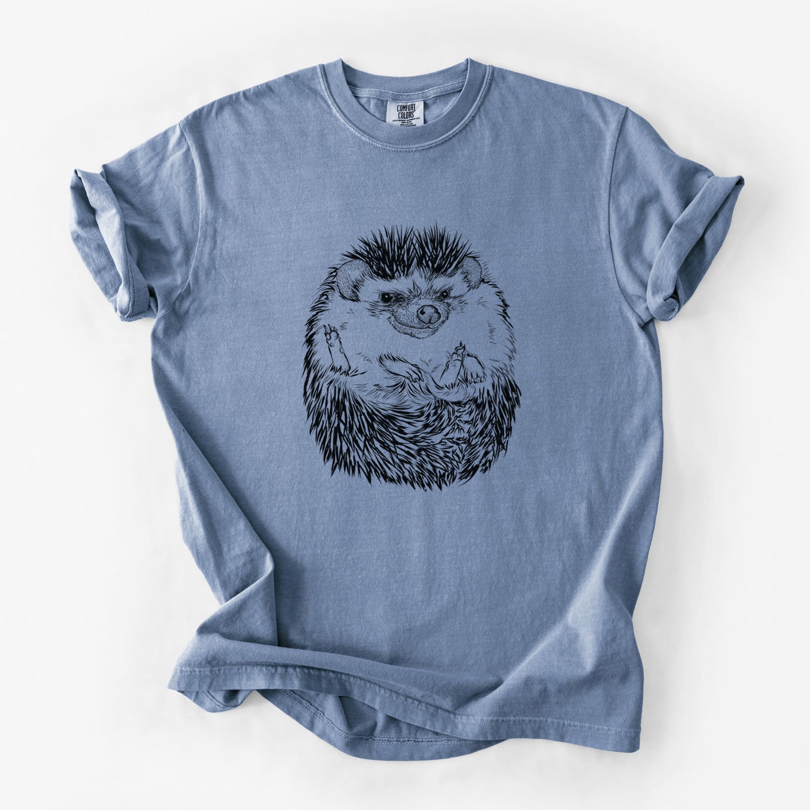 Blue jean Comfort Colors t-shirt laid flat, printed with a detailed black ink illustration of a hedgehog curled up and facing forward.