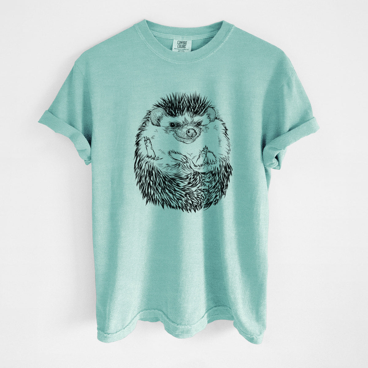 Chalky mint Comfort Colors t-shirt laid flat, printed with a detailed black ink illustration of a hedgehog curled up and facing forward.