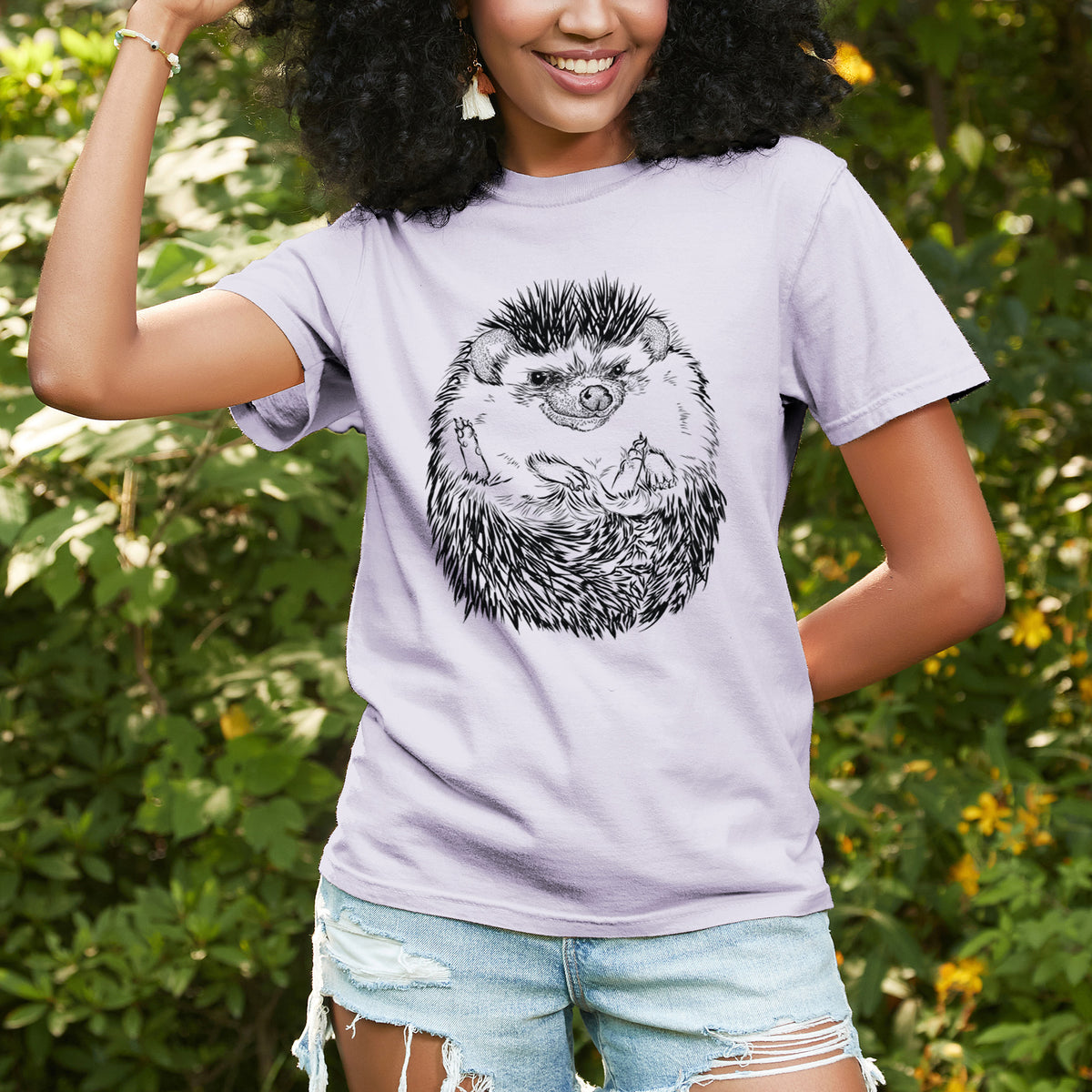 Woman wearing a Comfort Colors t-shirt printed with a detailed black ink illustration of a hedgehog curled up and facing forward, outdoors.