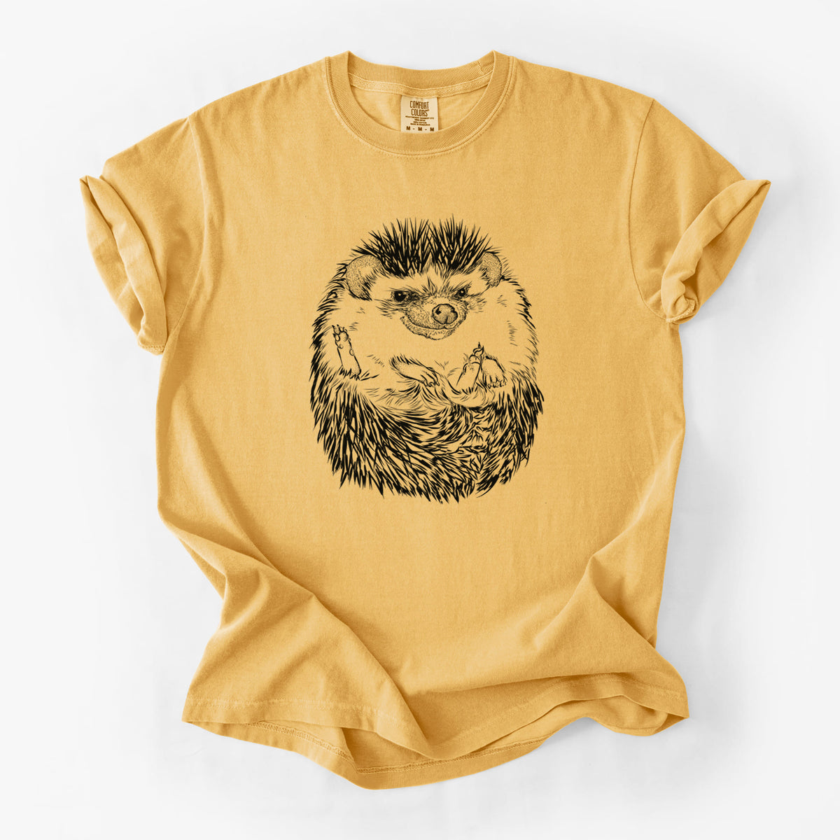 Golden wheat yellow Comfort Colors t-shirt laid flat, printed with a detailed black ink illustration of a hedgehog curled up and facing forward.