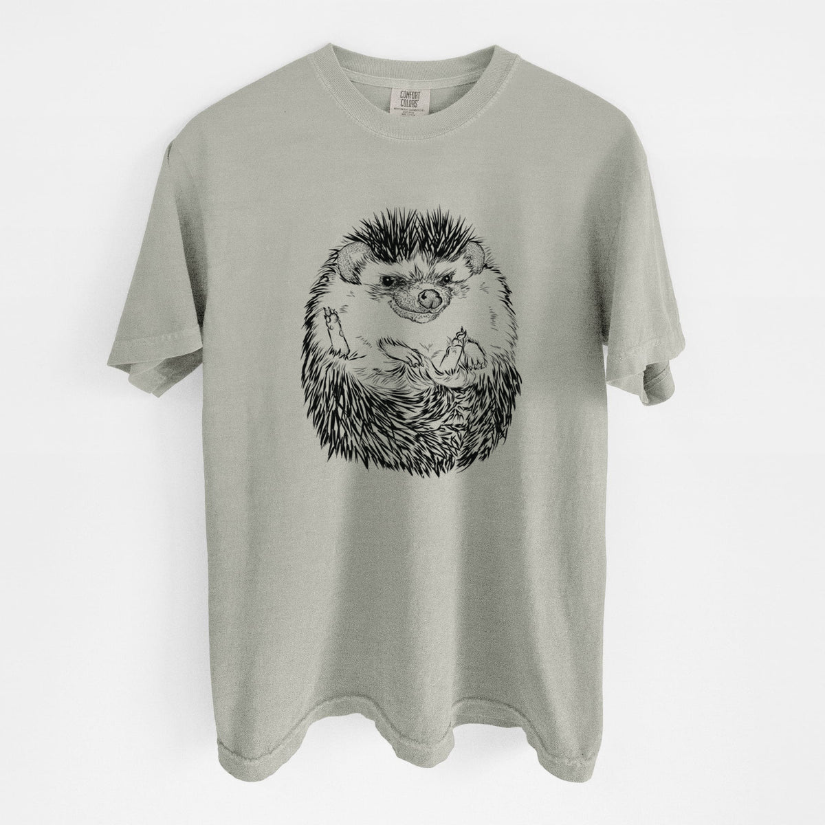 Sandstone beige Comfort Colors t-shirt laid flat, printed with a detailed black ink illustration of a hedgehog curled up and facing forward.