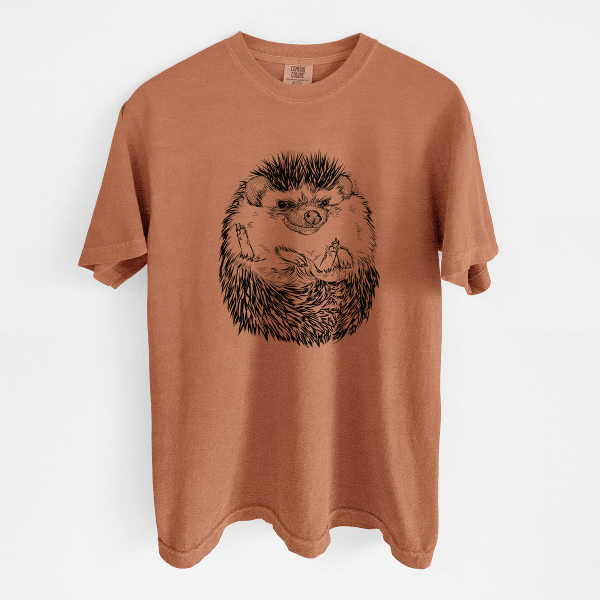 Yam burnt orange Comfort Colors t-shirt laid flat, printed with a detailed black ink illustration of a hedgehog curled up and facing forward.