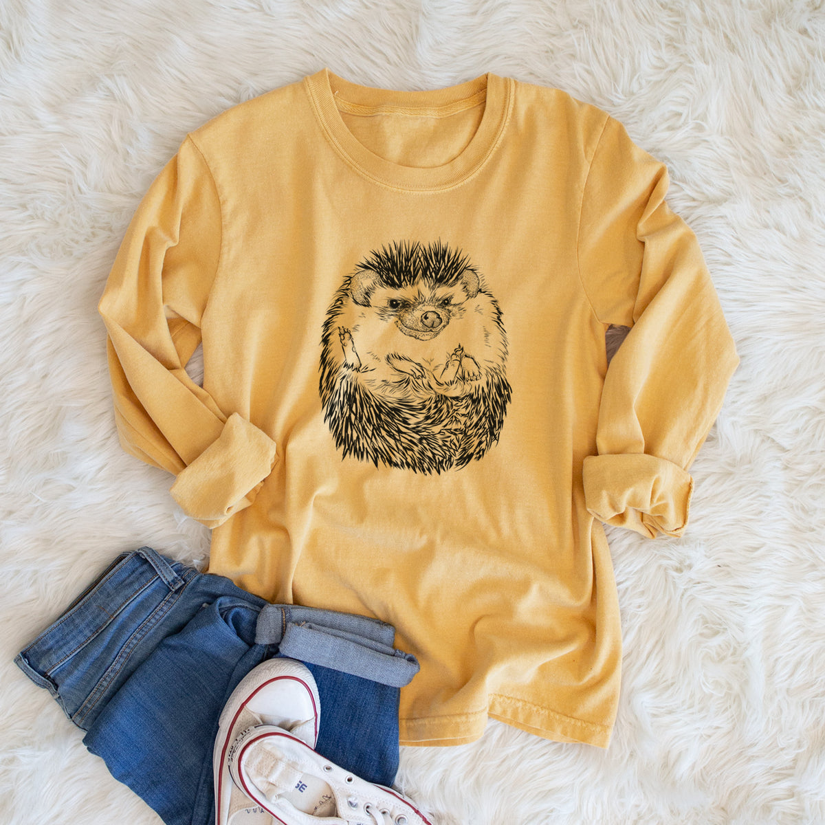 Golden wheat yellow Comfort Colors long sleeve shirt printed with a detailed black ink illustration of a hedgehog curled up and facing forward, shown in a lifestyle photo.