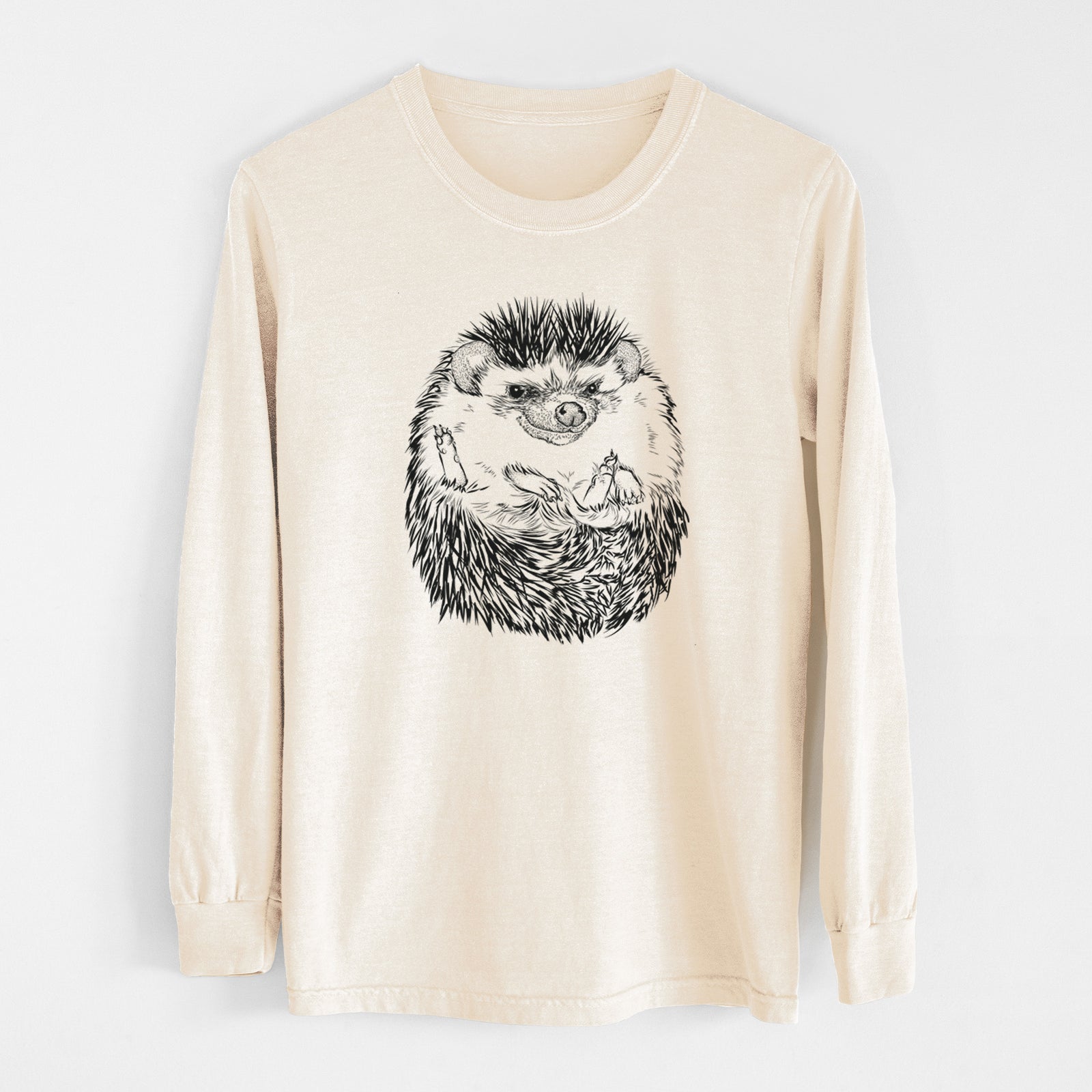 Ivory Comfort Colors long sleeve shirt laid flat, printed with a detailed black ink illustration of a hedgehog curled up and facing forward.