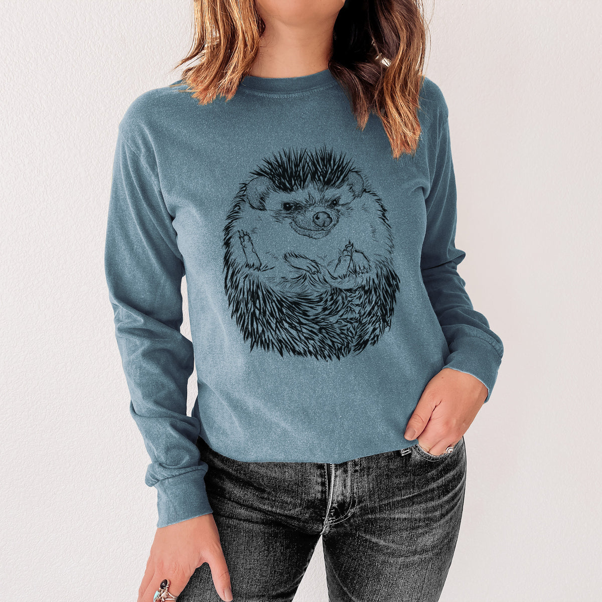 Steel blue Comfort Colors long sleeve shirt printed with a detailed black ink illustration of a hedgehog curled up and facing forward, shown in a lifestyle photo.