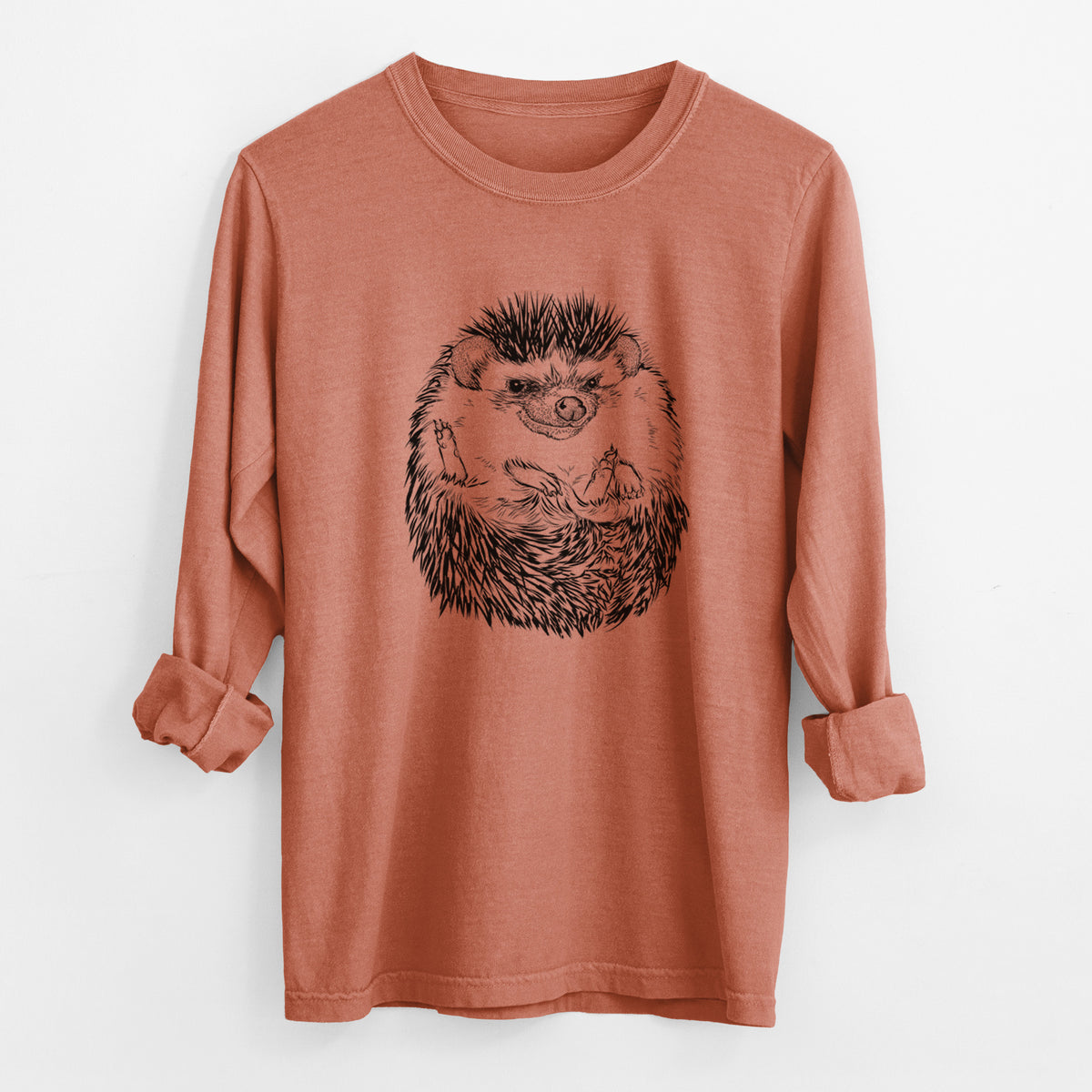 Yam burnt orange Comfort Colors long sleeve shirt laid flat with the cuffs rolled, printed with a detailed black ink illustration of a hedgehog curled up and facing forward.
