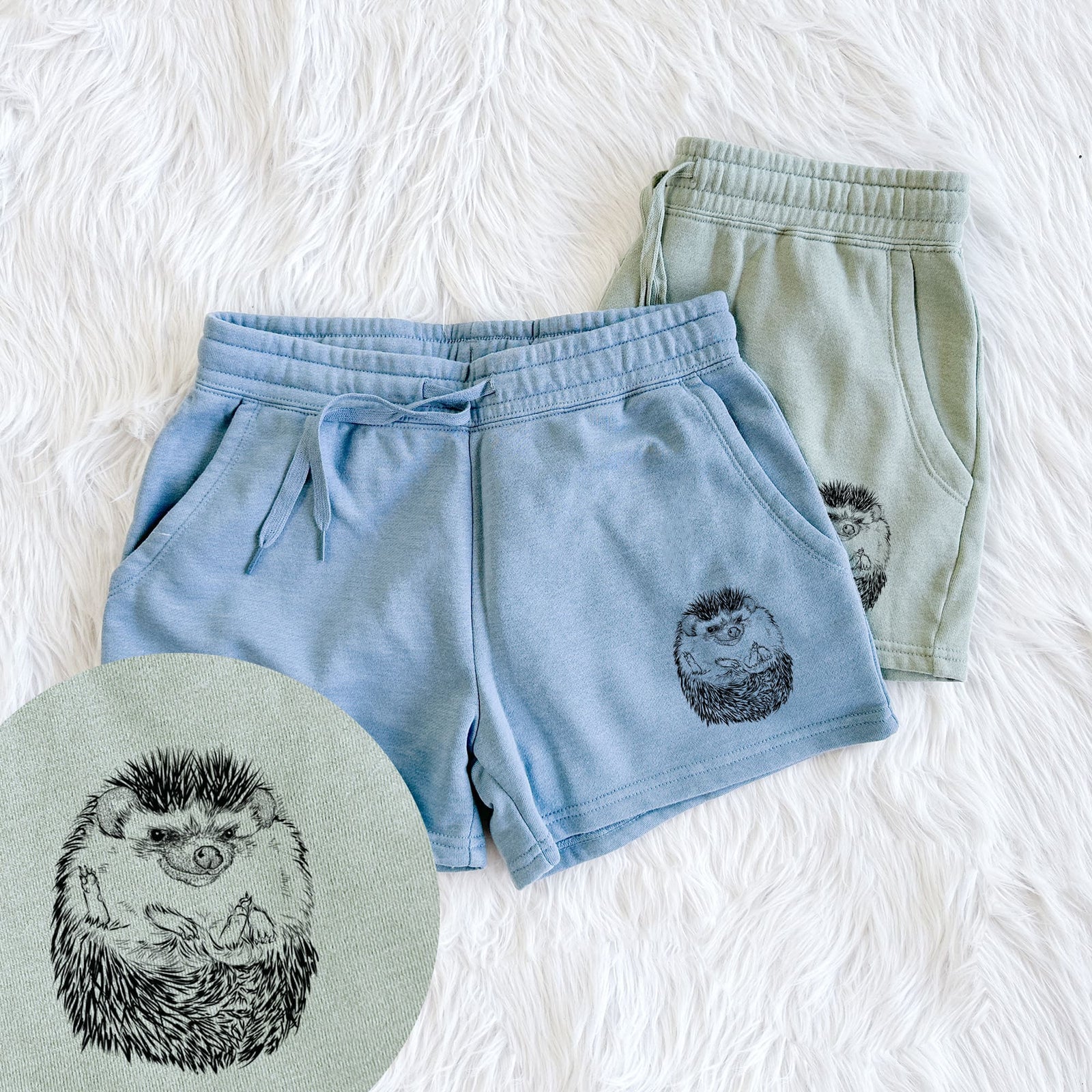 Two pairs of Cali Wave shorts in different colors printed with a detailed black ink illustration of a hedgehog curled up and facing forward, with a close-up of the print.