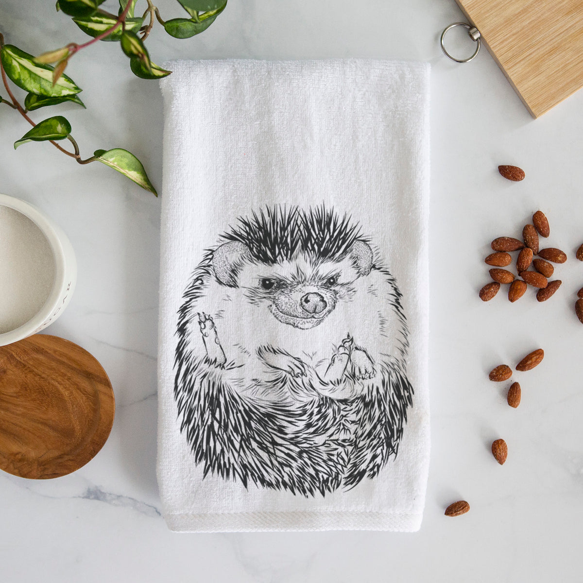 White hand towel printed with a detailed black ink illustration of a hedgehog curled up and facing forward.