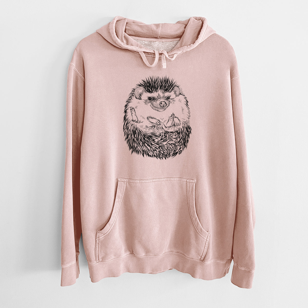 Dusty pink pigment dyed hoodie laid flat, printed with a detailed black ink illustration of a hedgehog curled up and facing forward.
