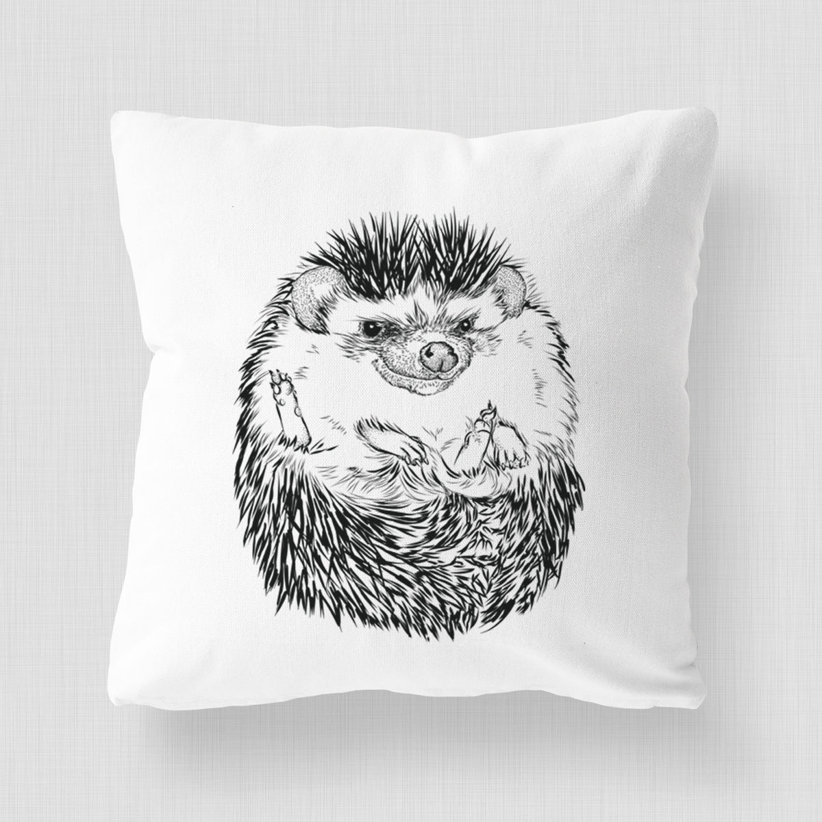 White pillow cover printed with a detailed black ink illustration of a hedgehog curled up and facing forward.