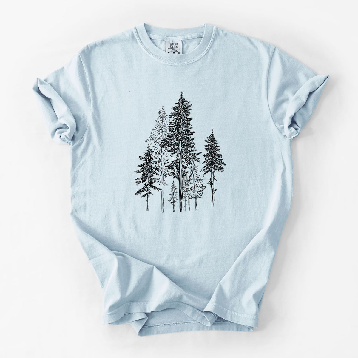 Chambray blue Comfort Colors t-shirt laid flat, printed with a black ink illustration of a forest of tall hemlock trees.
