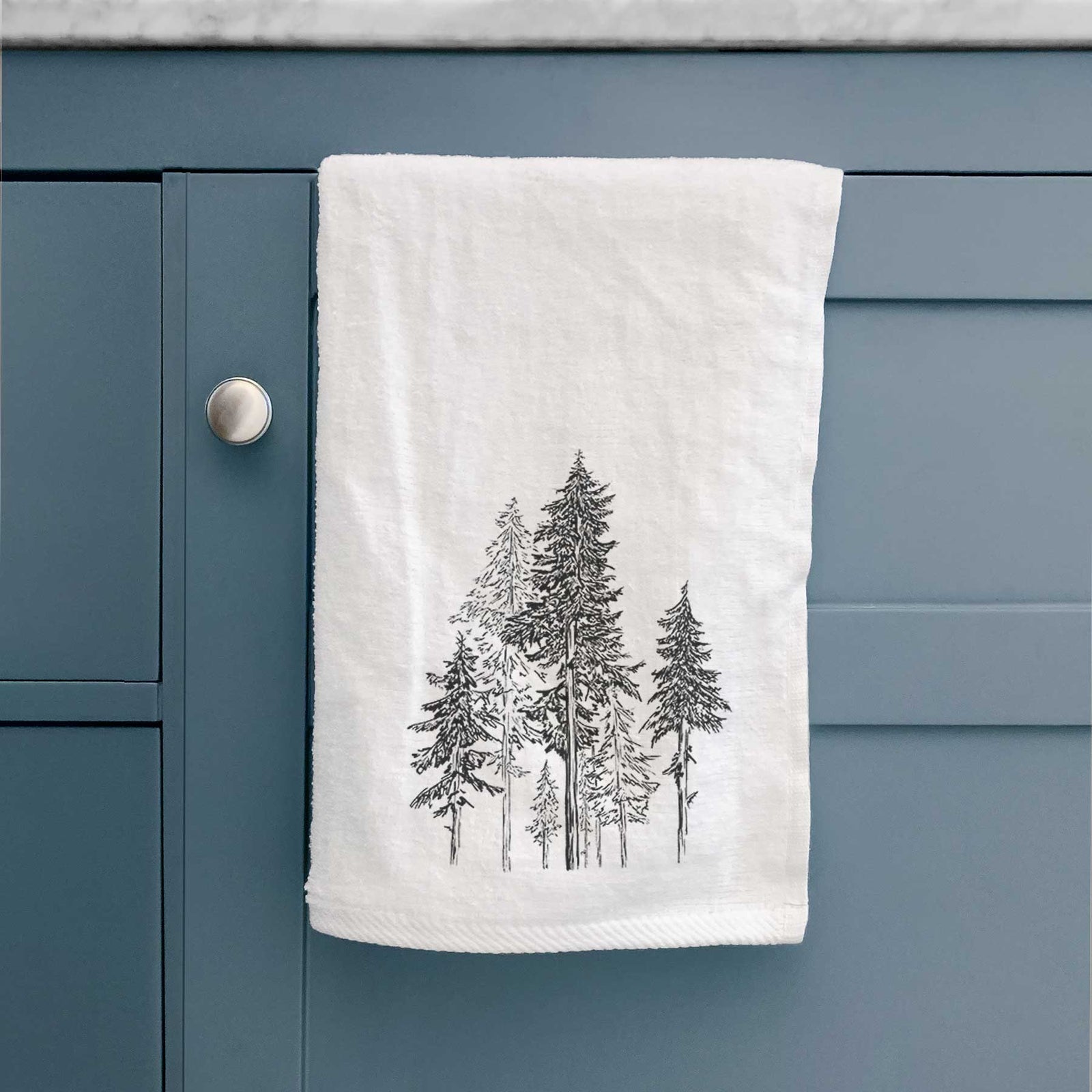 White hand towel printed with a black ink illustration of a forest of tall hemlock trees.