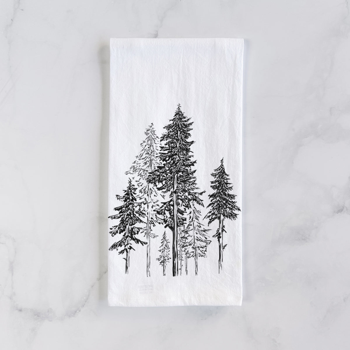 White cotton tea towel laid flat on marble, printed with a black ink illustration of a forest of tall hemlock trees.