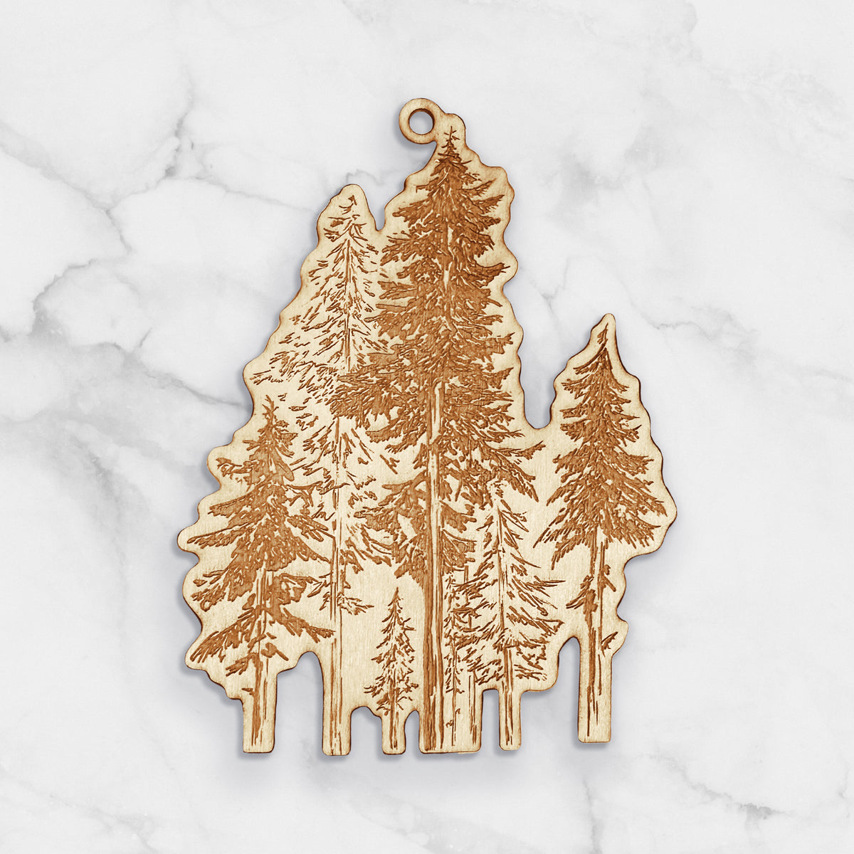 Wooden ornament featuring a detailed engraving of a forest of tall hemlock trees, on a marble surface.