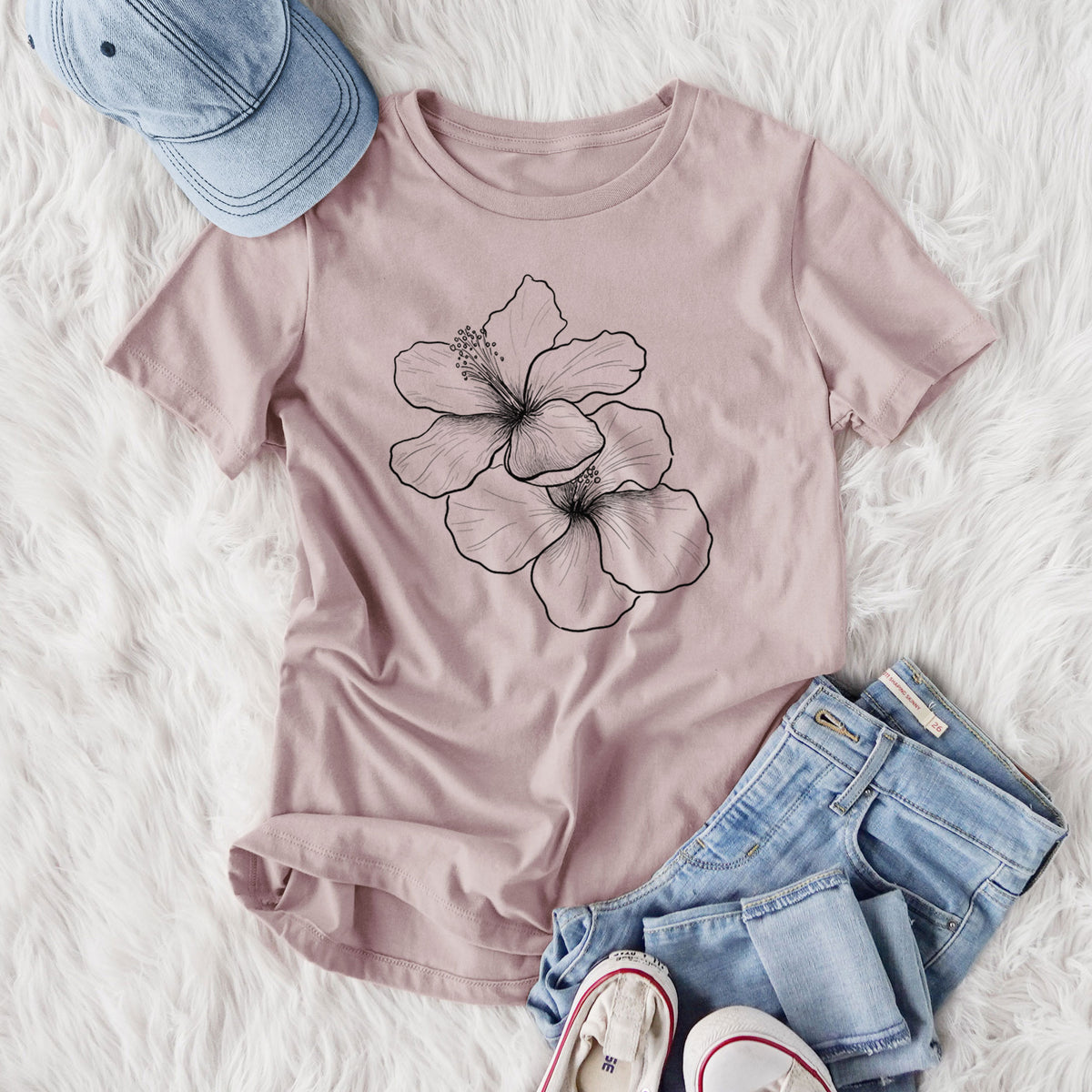 Women's relaxed fit cotton t-shirt printed with a black ink line drawing of three hibiscus flowers, styled flat on a white faux fur rug with jeans.