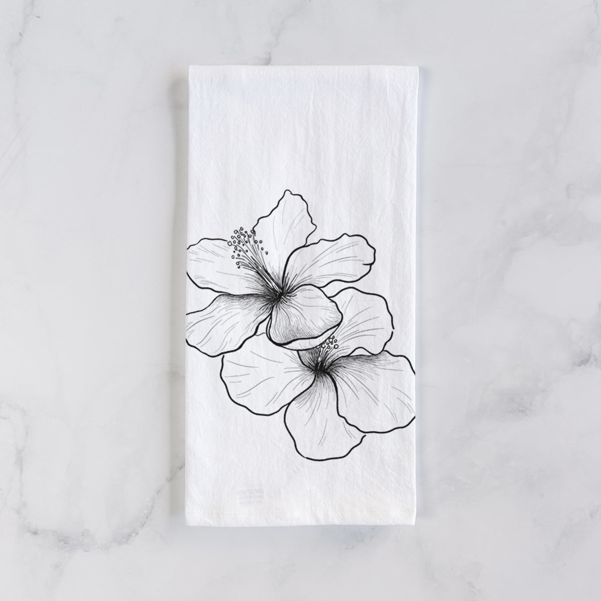 White cotton tea towel laid flat on marble, printed with a black ink line drawing of three hibiscus flowers.