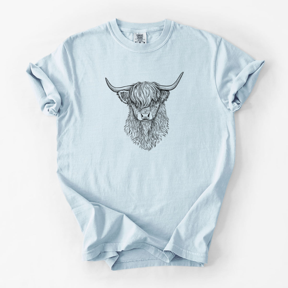 Chambray blue Comfort Colors t-shirt laid flat, printed with a detailed black ink portrait of a shaggy highland cow with long curved horns.
