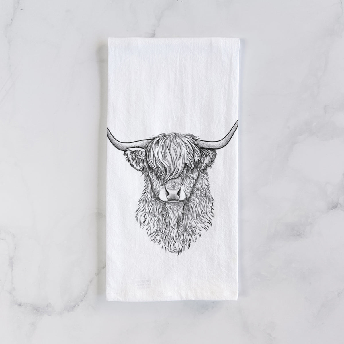 White cotton tea towel laid flat on marble, printed with a detailed black ink portrait of a shaggy highland cow with long curved horns.
