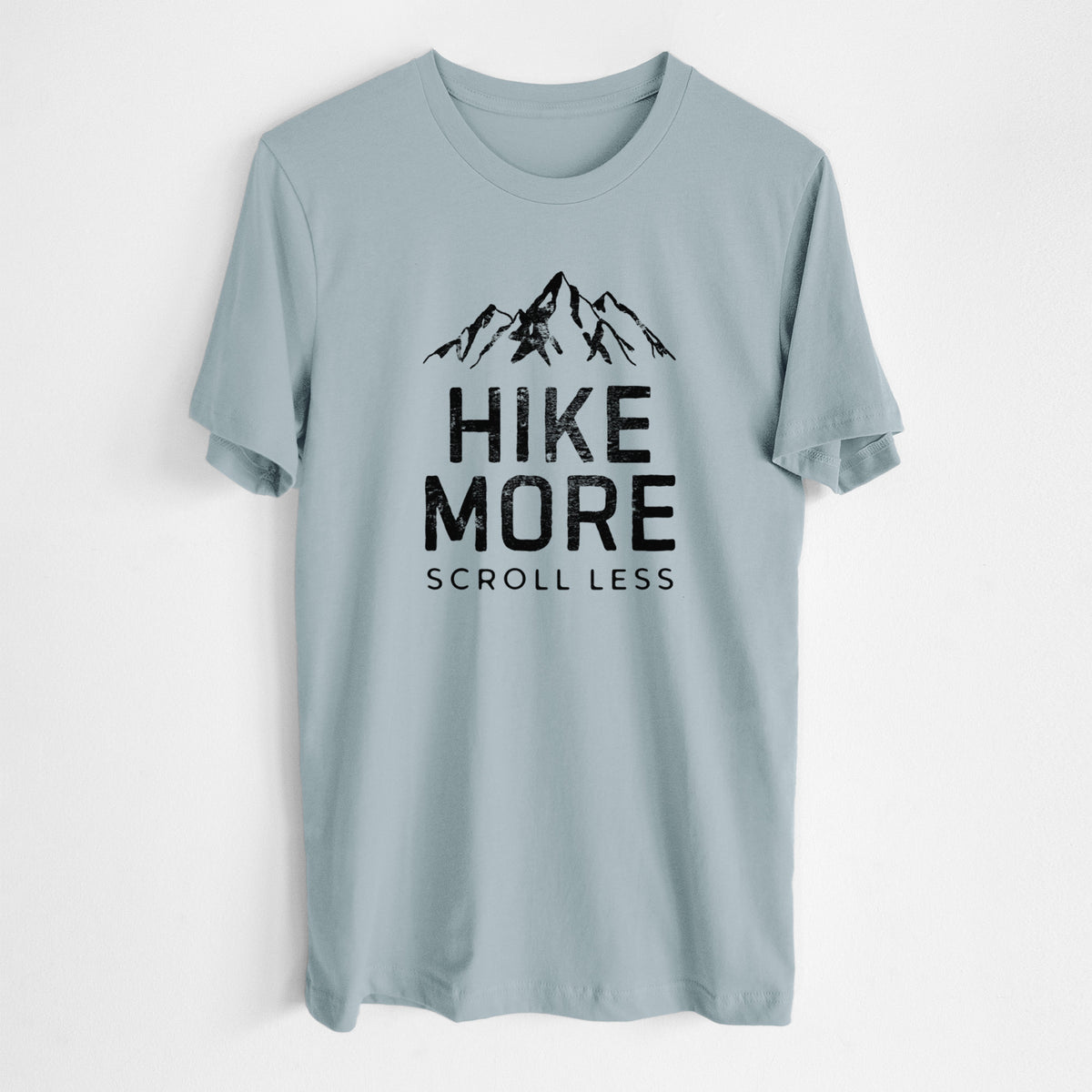 Vintage denim lightweight cotton t-shirt laid flat, printed with black mountain peaks above the bold words Hike More, Scroll Less.