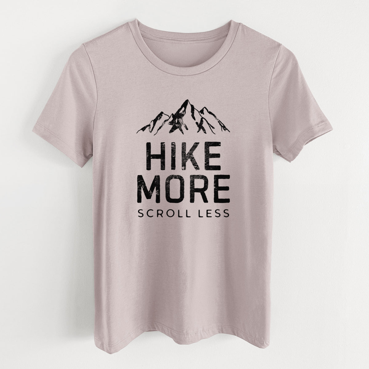 Pink gravel women's relaxed fit cotton t-shirt laid flat, printed with black mountain peaks above the bold words Hike More, Scroll Less.