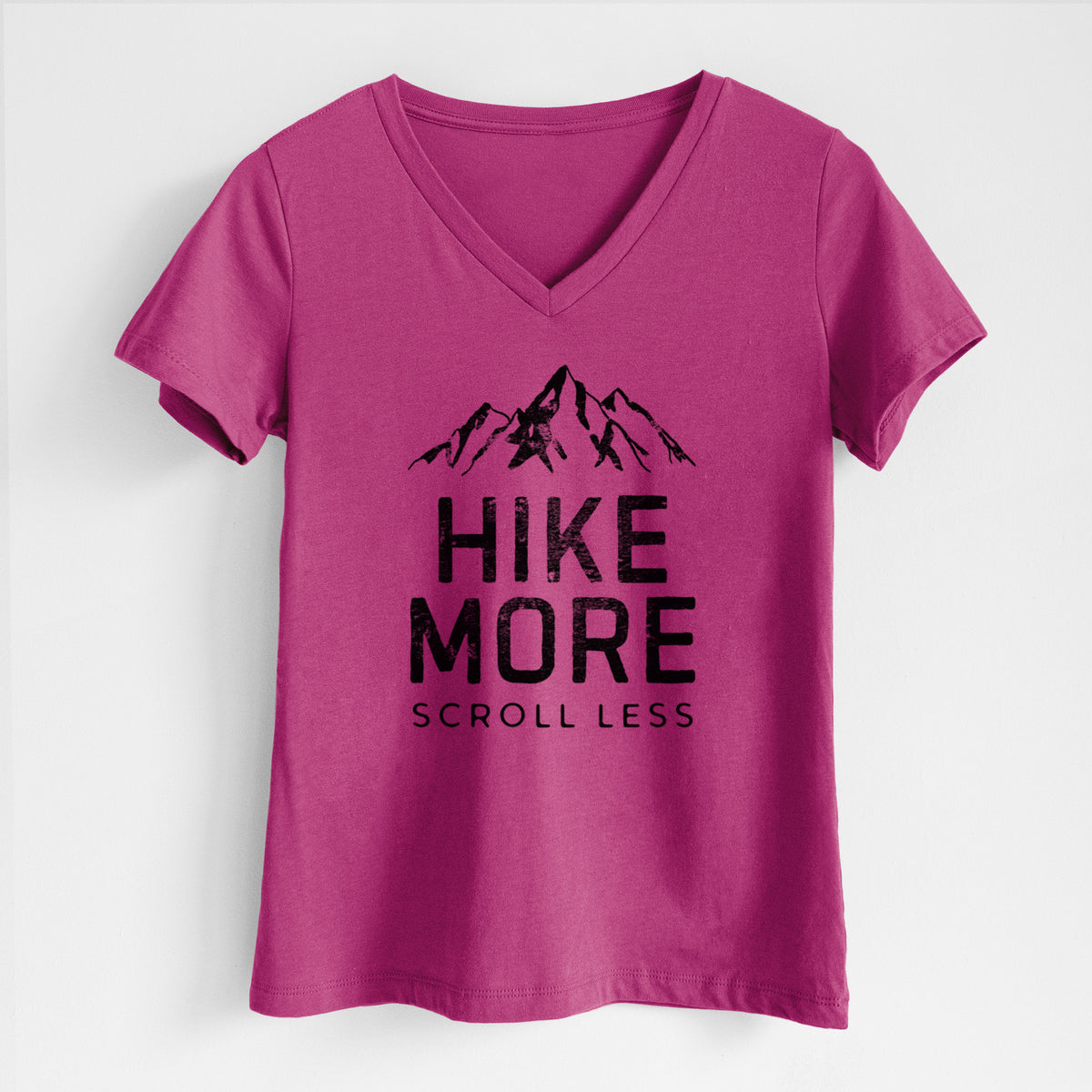 Berry pink women's relaxed fit cotton V-neck t-shirt laid flat, printed with black mountain peaks above the bold words Hike More, Scroll Less.