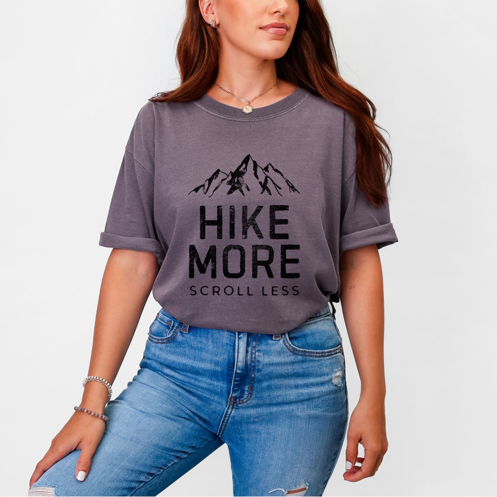 Blue jean Comfort Colors t-shirt laid flat, printed with black mountain peaks above the bold words Hike More, Scroll Less.