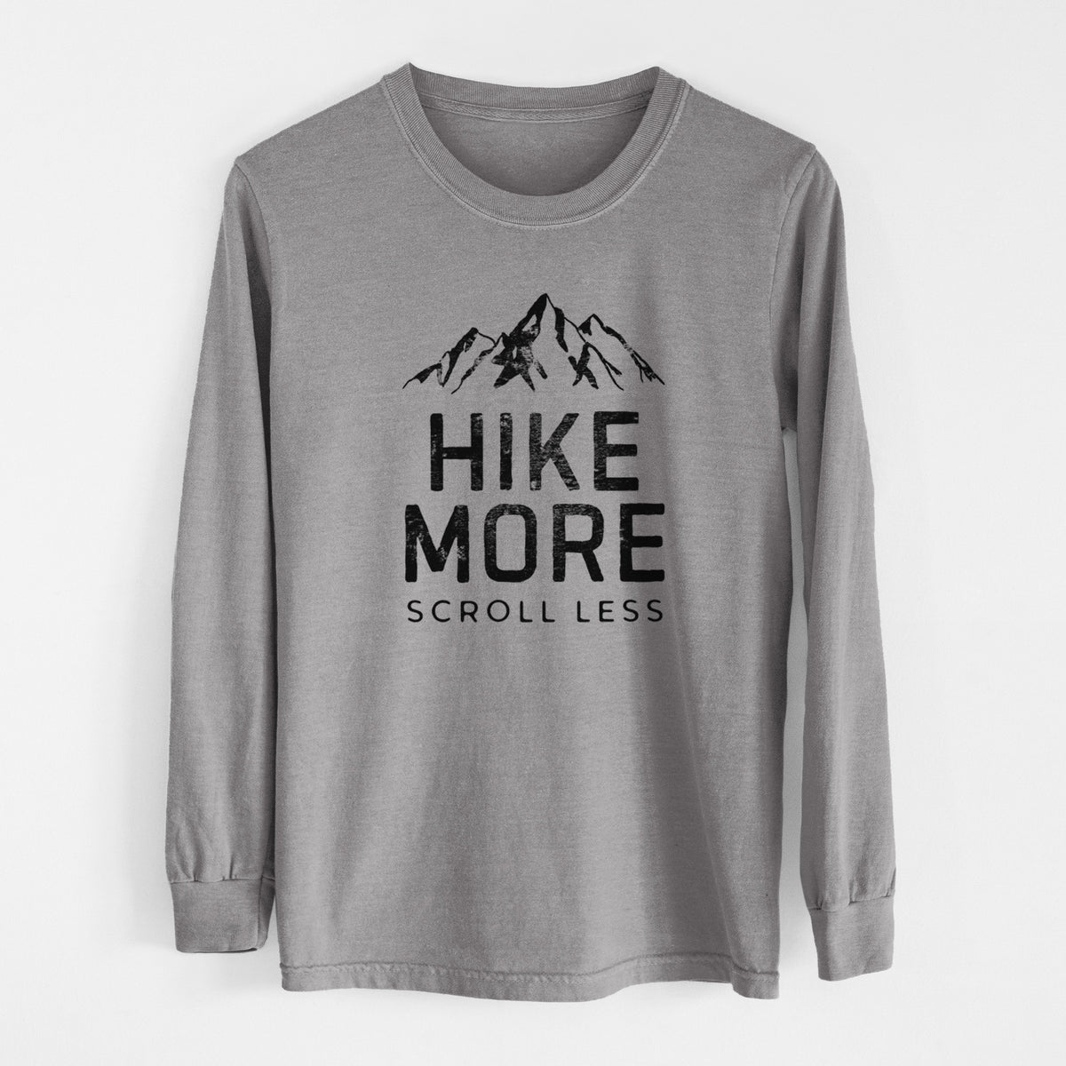 Grey Comfort Colors long sleeve shirt laid flat, printed with black mountain peaks above the bold words Hike More, Scroll Less.