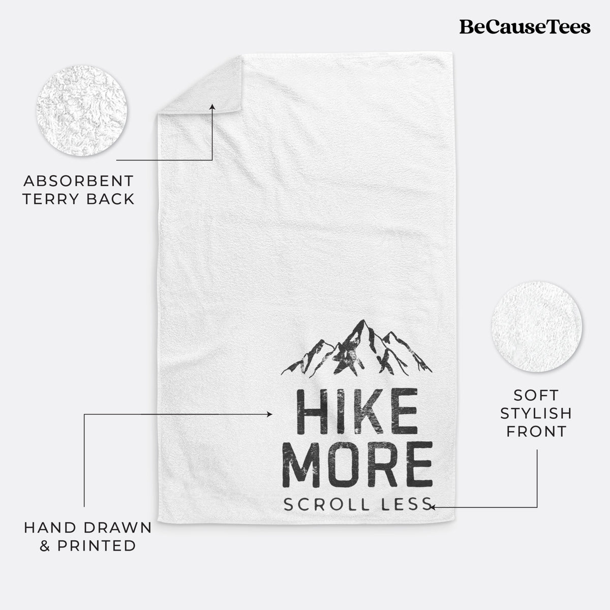 White hand towel printed with black mountain peaks above the bold words Hike More, Scroll Less.
