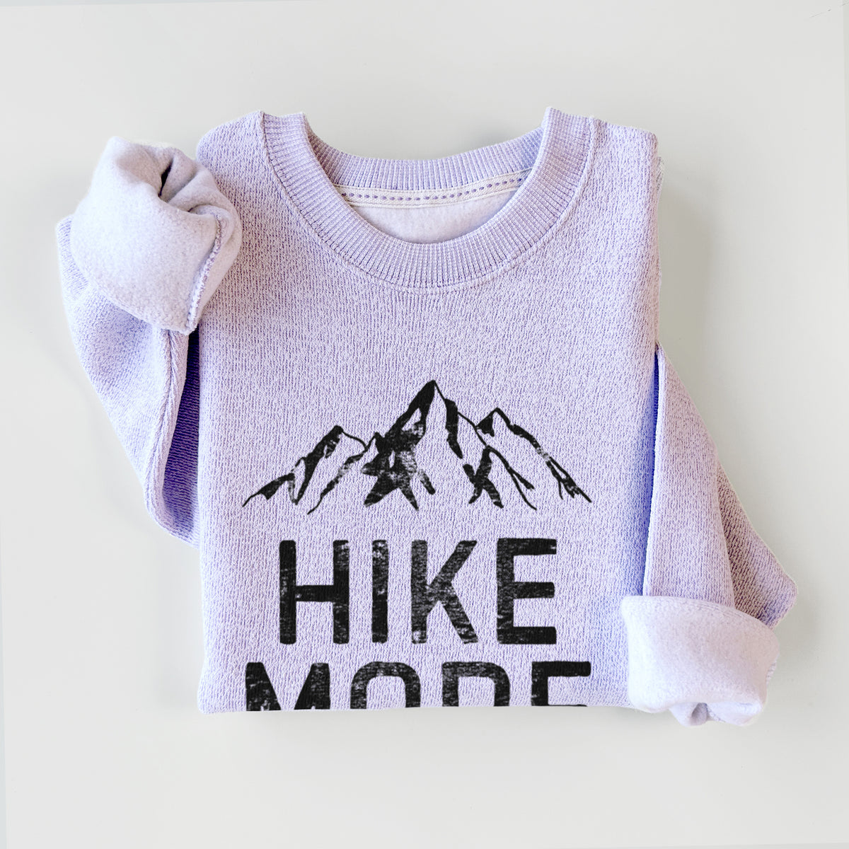 Ice purple knit sweatshirt printed with black mountain peaks above the bold words Hike More, Scroll Less, styled flat.
