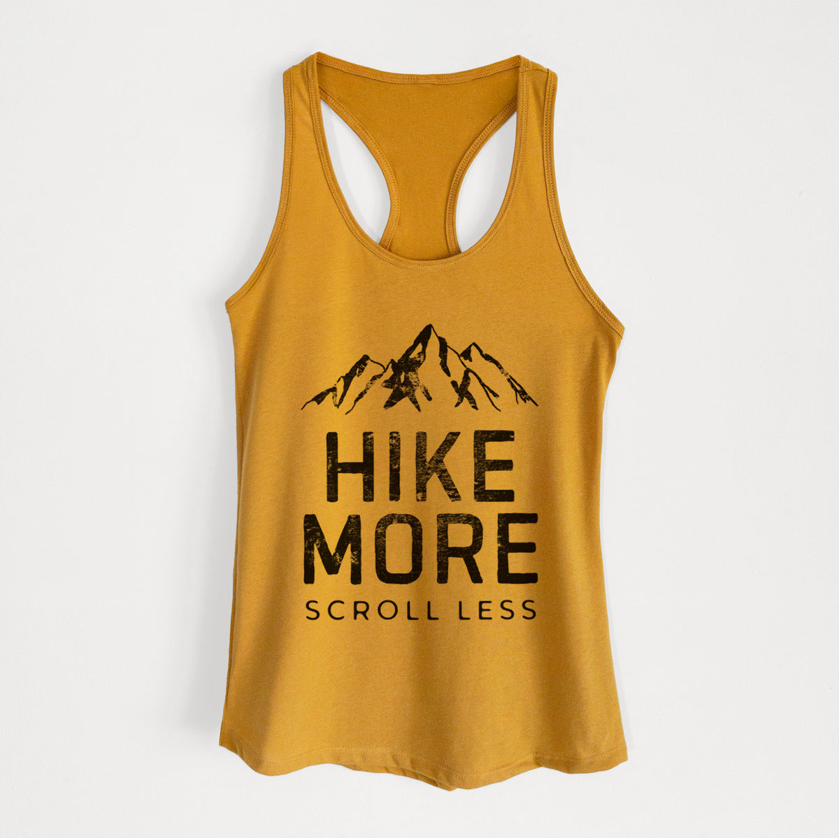 Gold women's racerback tank top laid flat, printed with black mountain peaks above the bold words Hike More, Scroll Less.