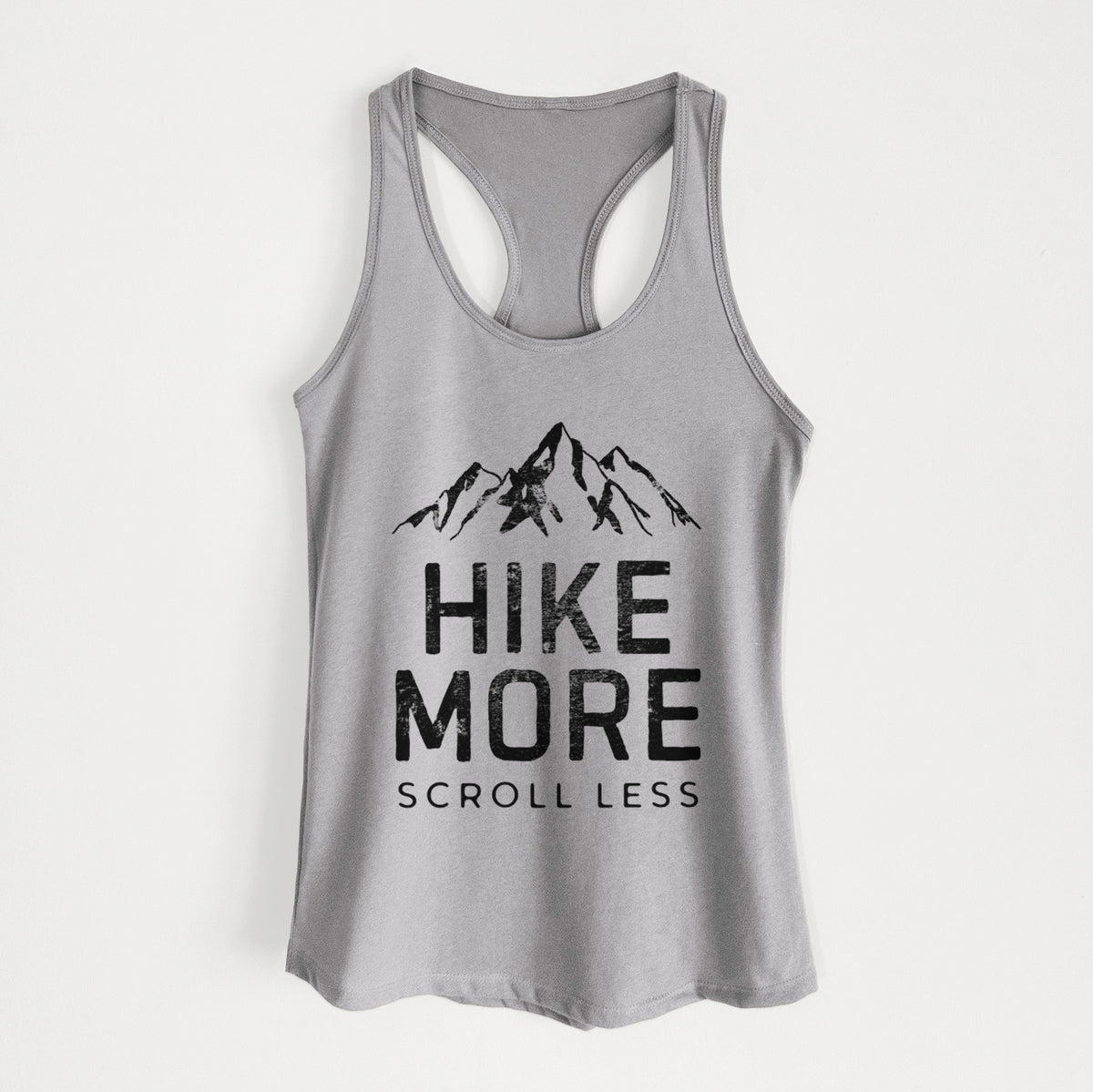 Heather grey women's racerback tank top laid flat, printed with black mountain peaks above the bold words Hike More, Scroll Less.