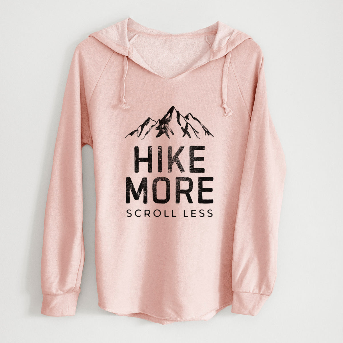 Blush pink women's Cali Wave hooded sweatshirt laid flat, printed with black mountain peaks above the bold words Hike More, Scroll Less.